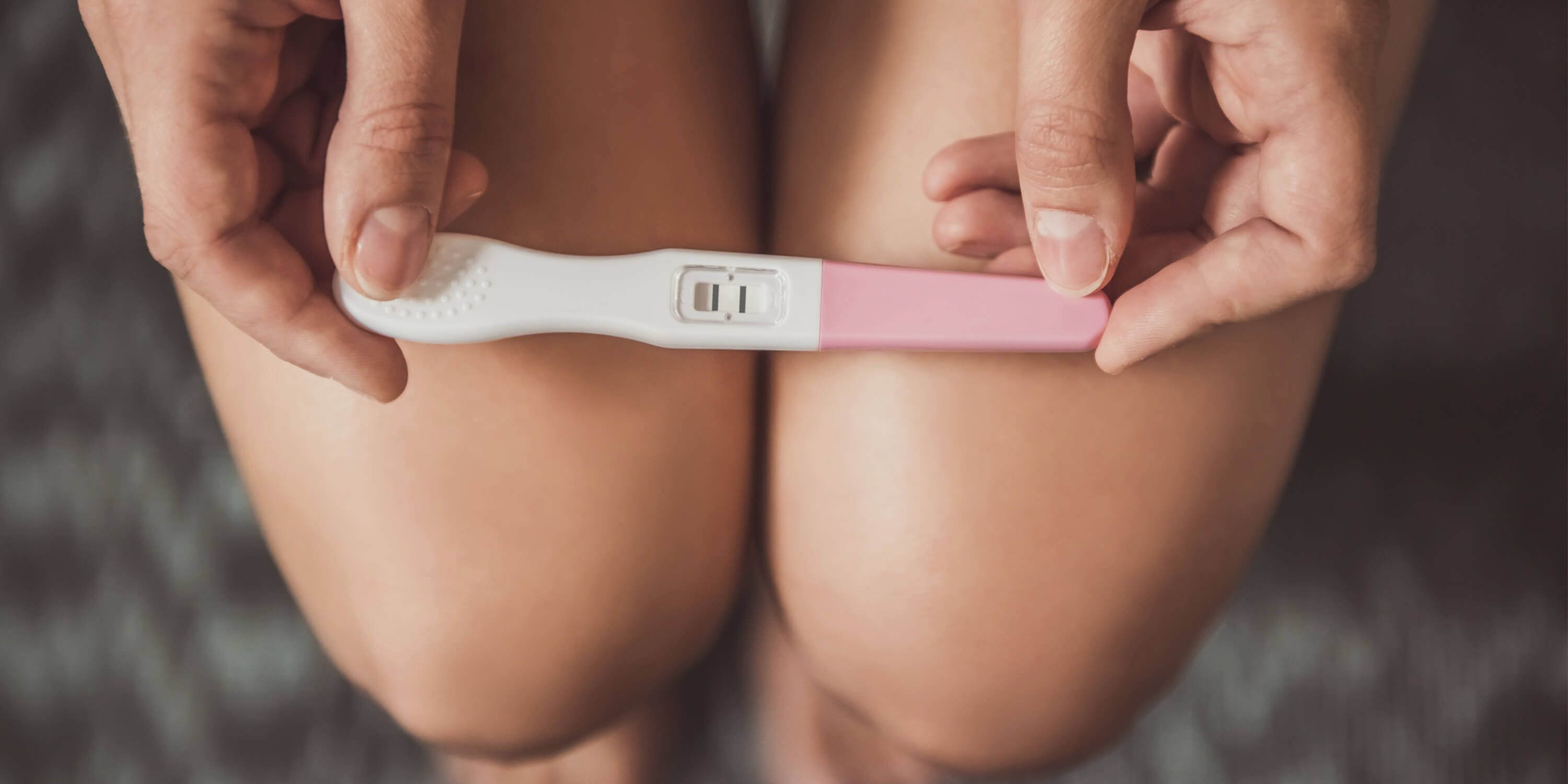 Una giovane donna tiene tra le mani un test di gravidanza. 