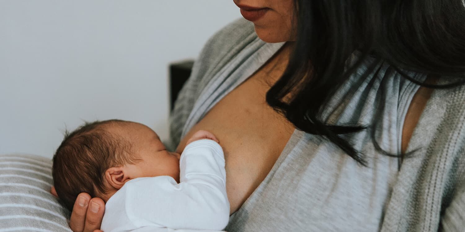 newborn baby drinking from mothers breast 