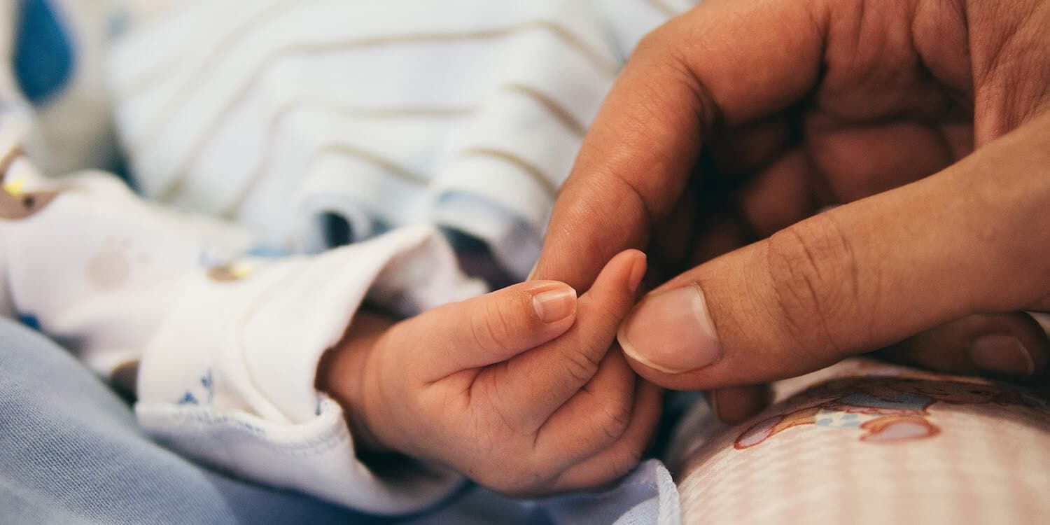 Close up, mother lovingly holding baby's hand