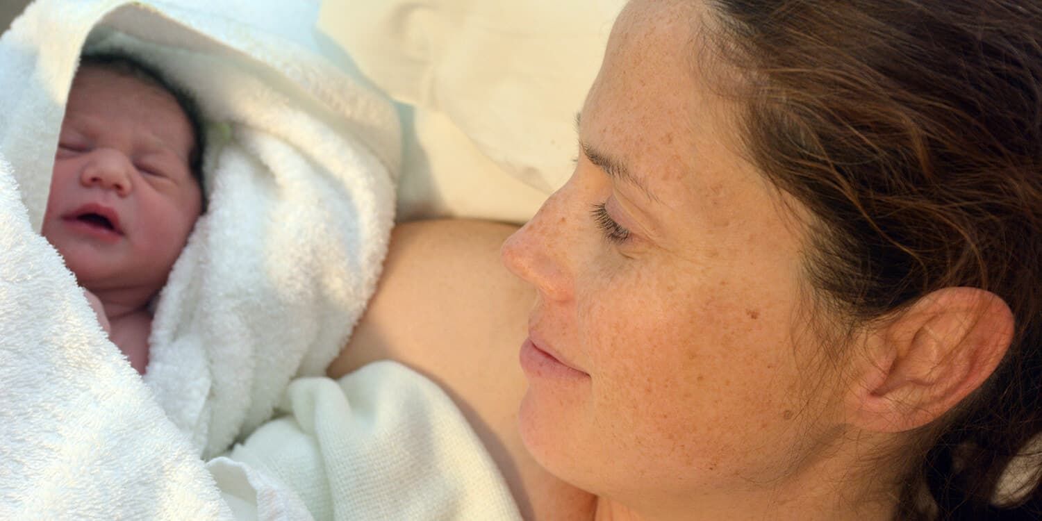 mother holding newborn in her arm after birth