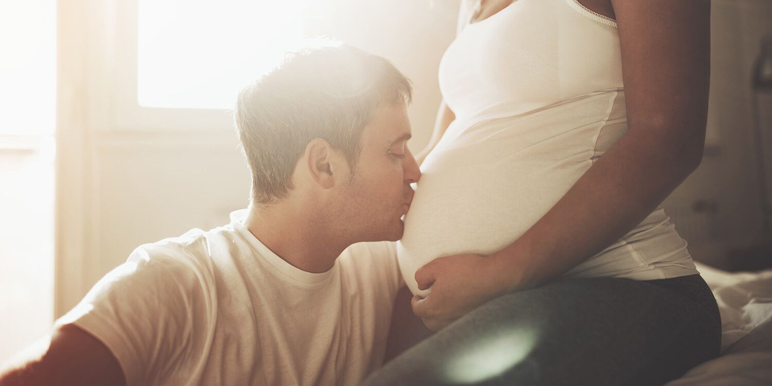 Man pussar gravid kvinna på magen.