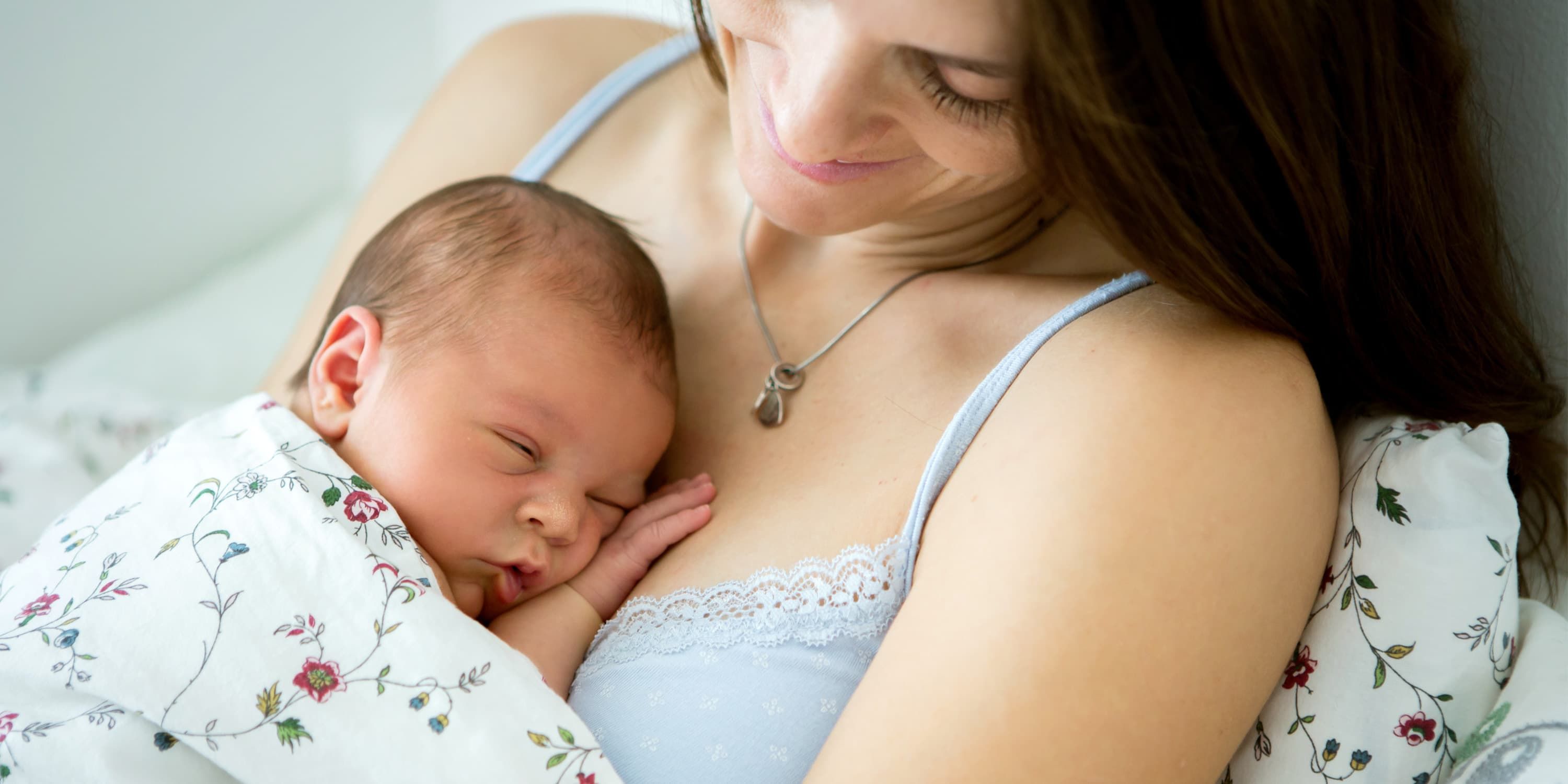 Mother lying in bed, newborn baby lying on her chest