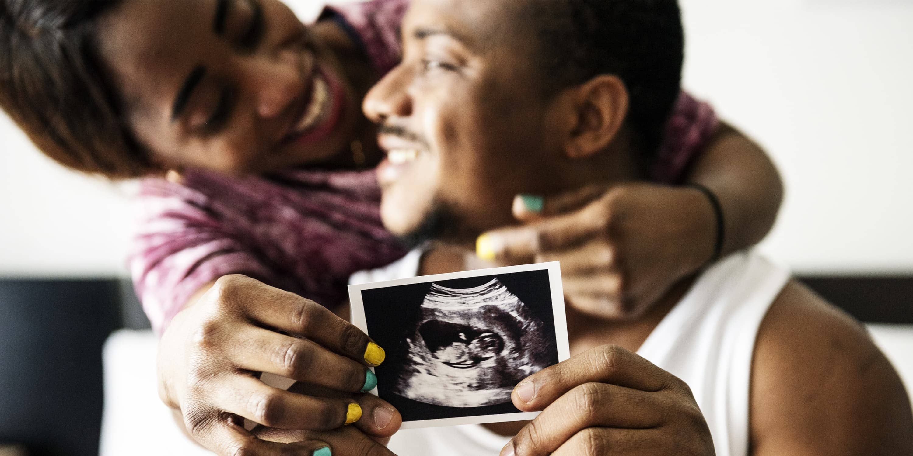 Pareja negra enseñando una ecografía de su bebé