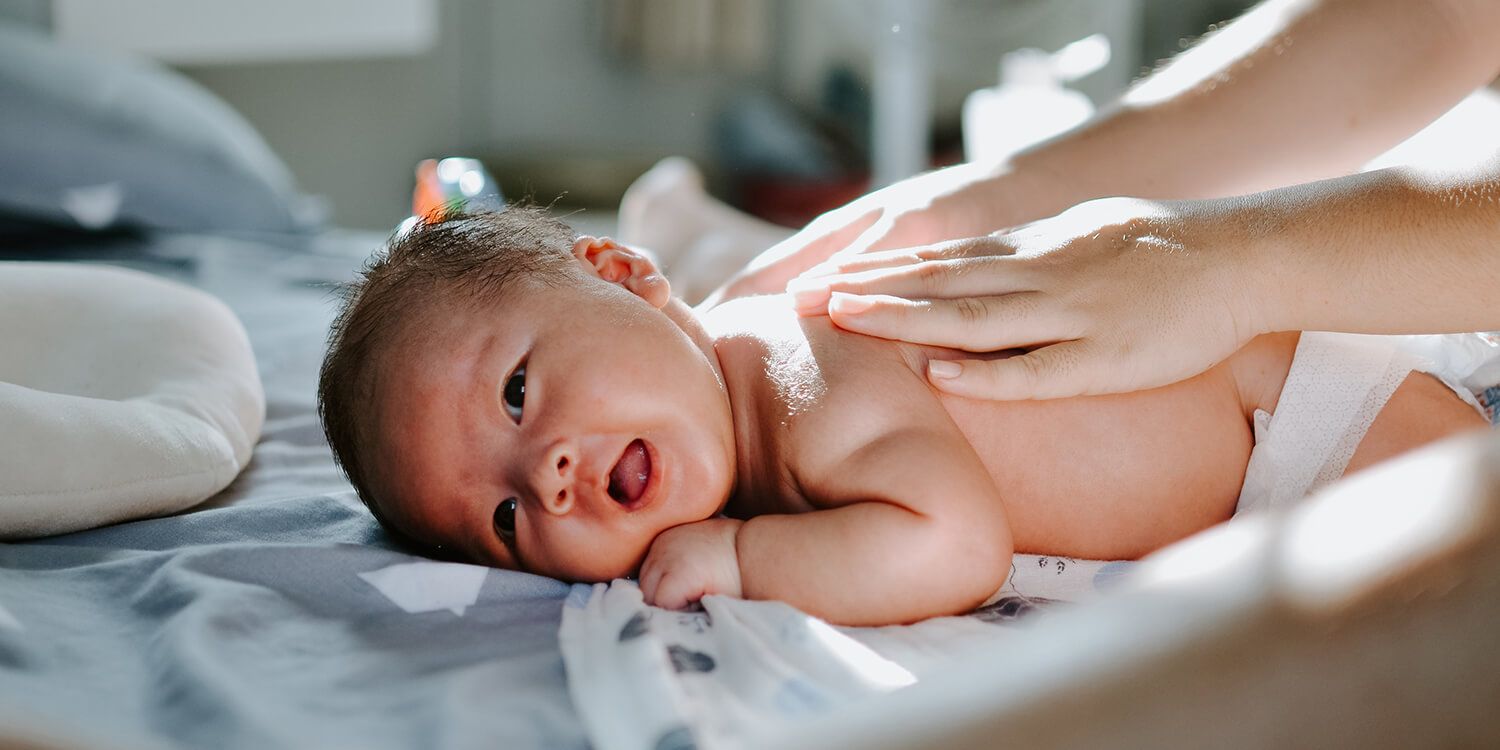 Mutter massiert ihr Baby sanft auf dem Rücken