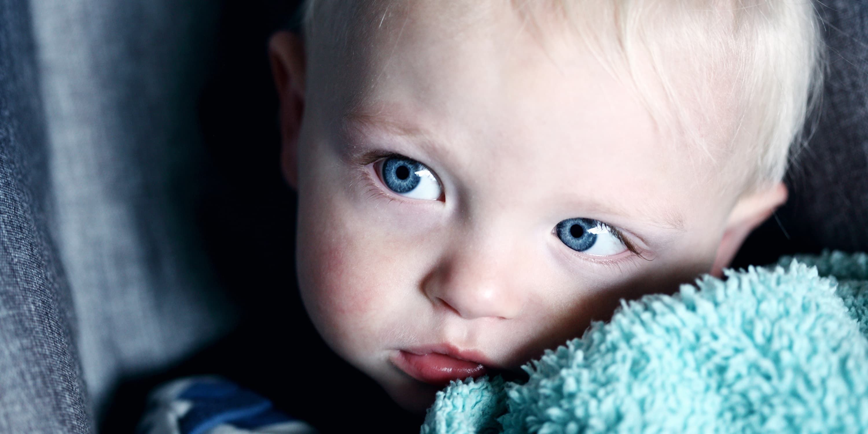 Baby hält sich Handtuch an die Wange