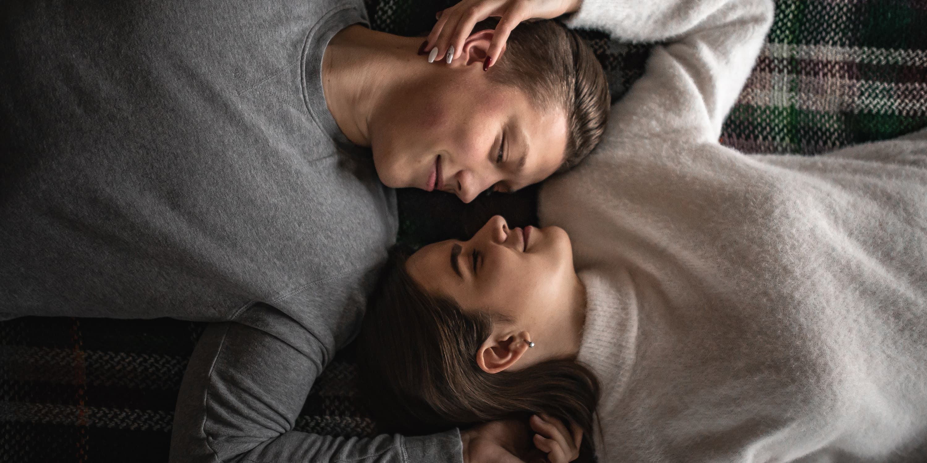 Man and woman lying side by side and smiling at each other