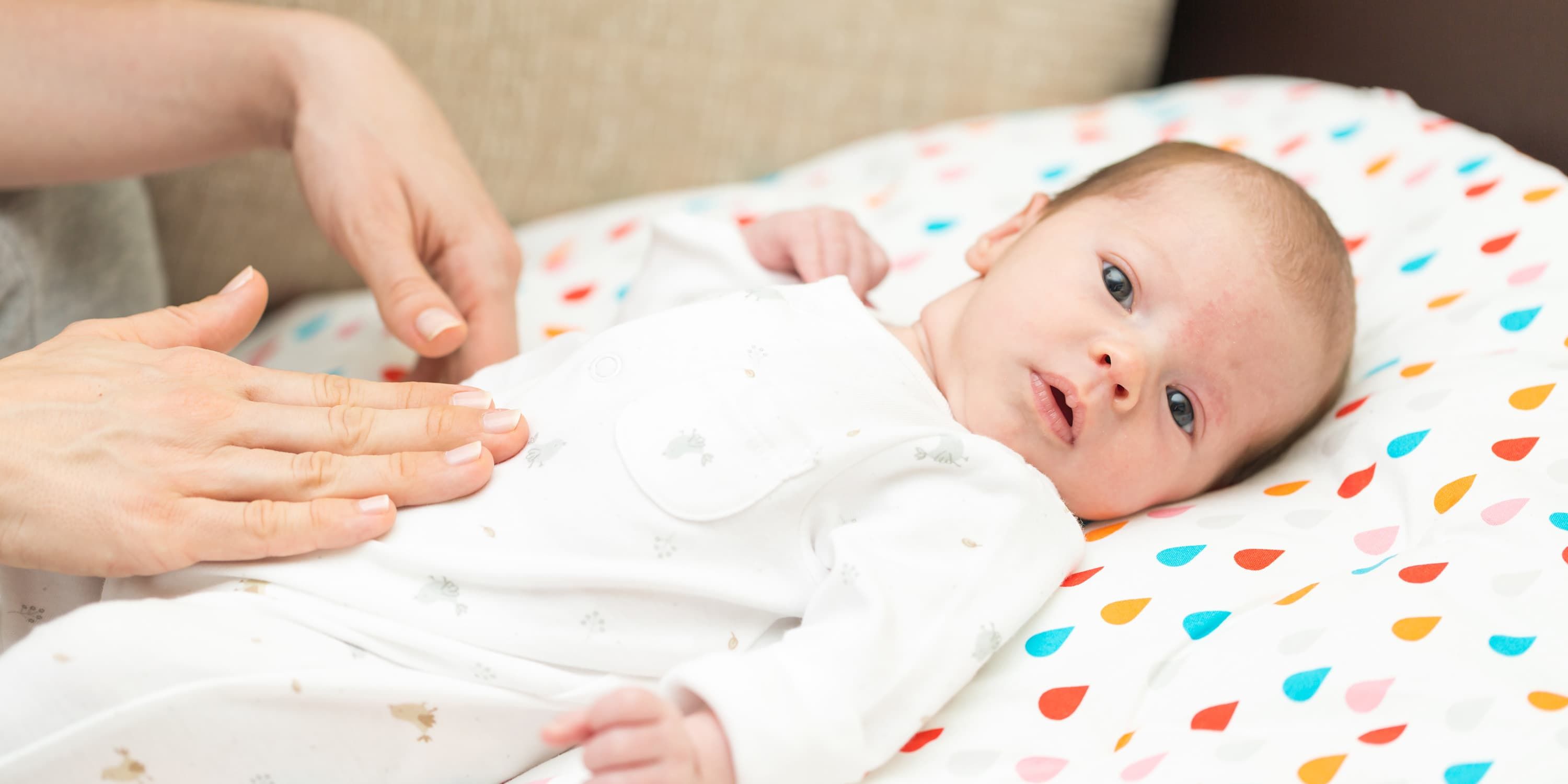 Mutter massiert Baby sanft den Bauch