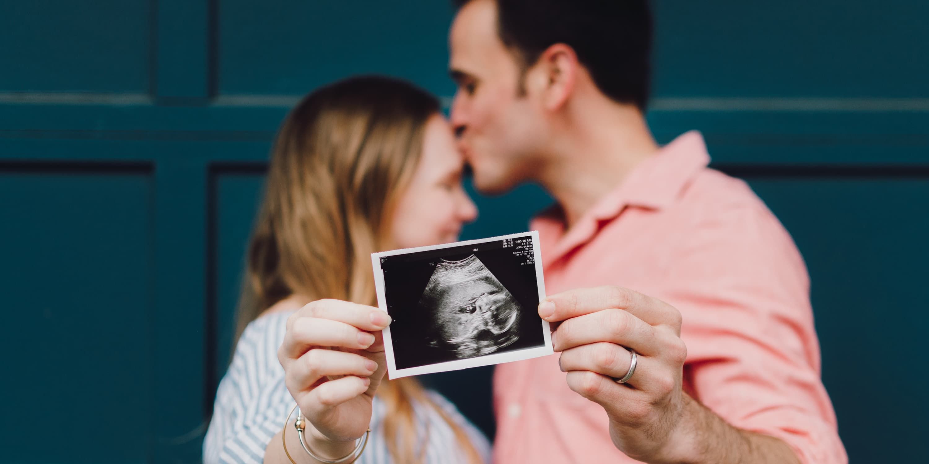 Giovane coppia mostra alla fotocamera l'ecografia del proprio bambino