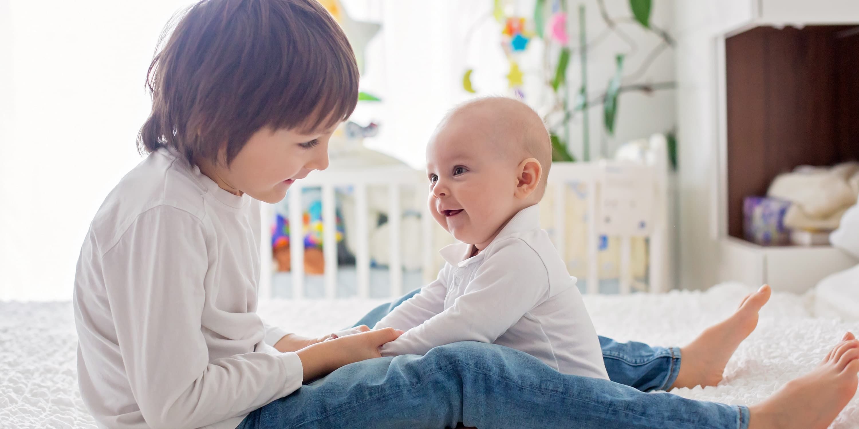 Sibling playing with baby on the floor